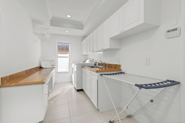A modern kitchen with white cabinets, a wooden countertop, a built-in oven, and a drying rack. - Villa Cape Coral Florida (Cape Coral)