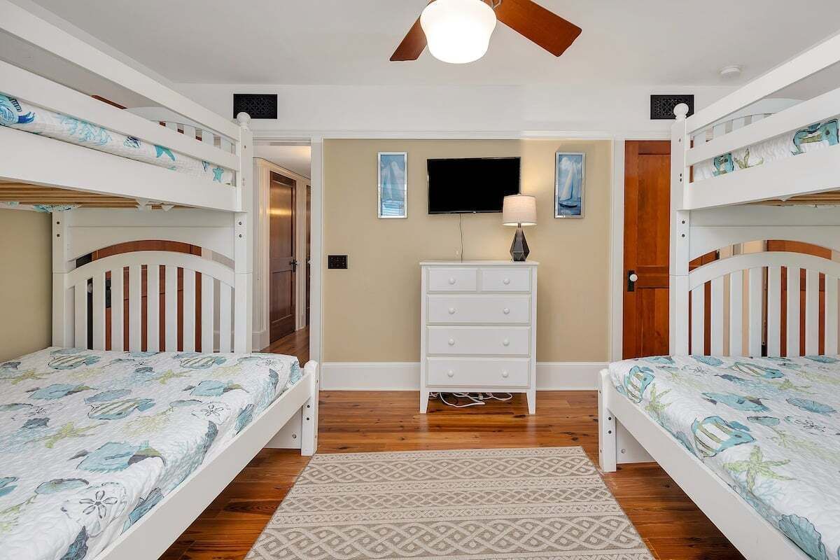 Une chambre avec des lits superposés, une télévision, une commode et un tapis à motifs.