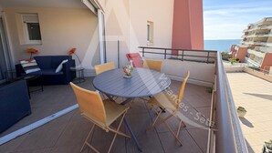 A balcony with a round table and chairs, a sofa, and a potted plant.