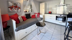 A modern kitchen with white cabinets, a stainless steel oven, and a black countertop.