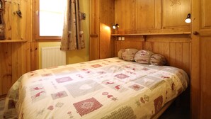 Um quarto de madeira com uma cama, uma janela com cortinas e armários de madeira.