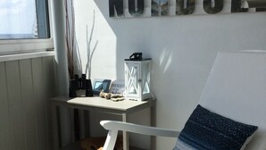 A room with a white rocking chair, a small table with a lantern, and a wall with the word "NORDSEE" displayed. - FeWo WeserWeitblick in the 20. Floor in the Columbus Center  (Mitte)