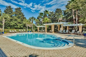 A swimming pool with lounge chairs and a pergola, surrounded by trees.