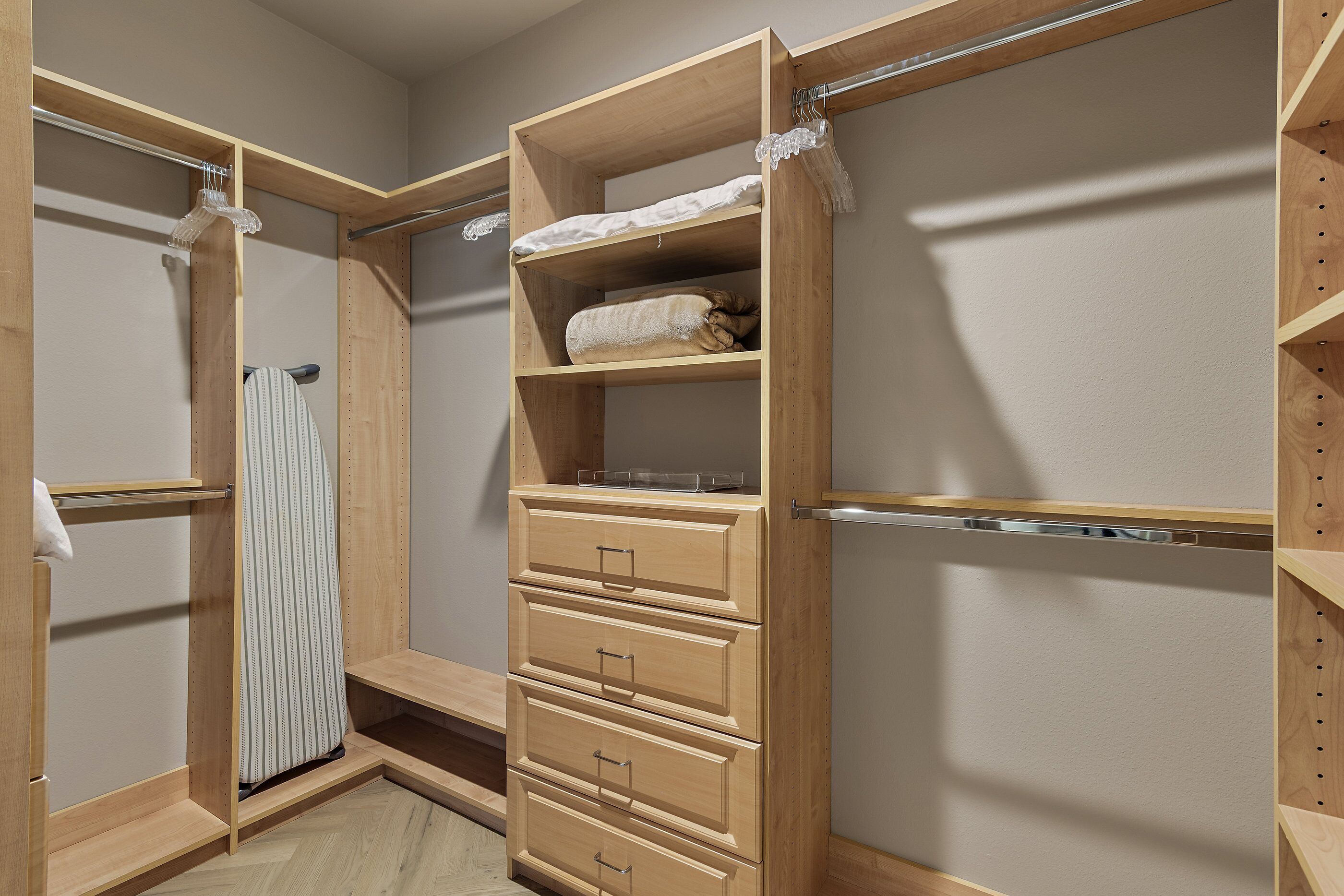 A walk-in closet with wooden shelving, a hanging rod, and a mirrored closet door.