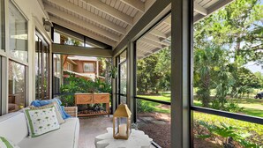 A modern interior with a white sofa, a lantern, and a view of a lush garden through large windows. - Luxury Bayside Sandestin, Beach, 2 Golf Carts (Miramar Beach)