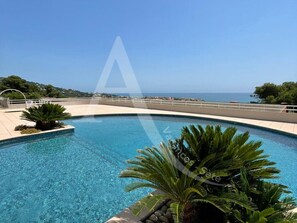 A clear blue swimming pool with a view of the sea, surrounded by greenery and a paved deck. - 2 CHAMBRES, LARGE TERRASSE VUE UNIQUE, PISCINE, TENNIS (Sète)