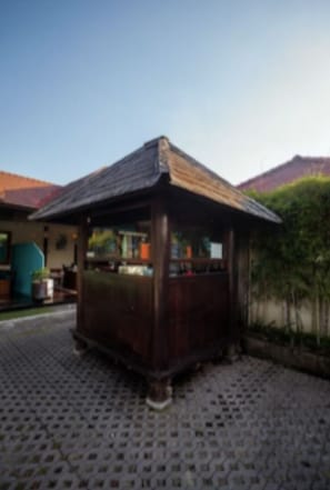 A small wooden structure with a sloped roof, possibly a gazebo or a small pavilion, situated on a cobblestone surface. - 5-bedroom private villa in Seminyak, offering daily breakfast, full-time private chef, airport transfers, complimentary massages, housekeeping, and a dedicated driver. (Seminyak)