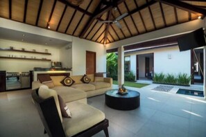 A modern interior with a sofa, a round table, and a kitchen area. - 5-bedroom private villa in Seminyak, offering daily breakfast, full-time private chef, airport transfers, complimentary massages, housekeeping, and a dedicated driver. (Seminyak)