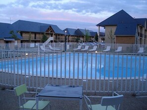 A swimming pool with a white fence, lounge chairs, and a table. - PROXIMITY HONFLEUR WIFI PARKING SWIMMING POOL (Equemauville)