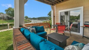 A covered patio with a brick bench, a table, and chairs, overlooking a body of water and a dock. - Lake Norman Dream Condo! 1st Floor, Lake View Lake Norman Vacation Rental (Cornelius)