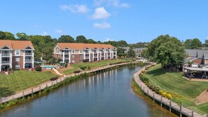 A riverside hotel with multiple-story buildings, a walking path along the water, and well-maintained lawns. - Lake Norman Dream Condo! 1st Floor, Lake View Lake Norman Vacation Rental (Cornelius)