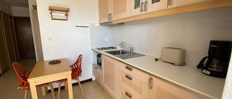 A compact kitchen with wooden cabinets, a sink, a toaster, and a coffee maker.