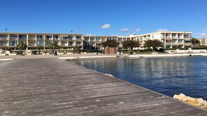 A waterfront hotel with a wooden pier extending into the water, featuring multiple balconies and a pool area. - Cozy apartment near Thermes with balcony, pets allowed (Balaruc-les-Bains)
