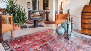 A living room with a fireplace, a large rug, and a wooden cabinet. - Homerez - House in Reignier-Esery (Reignier-Esery)