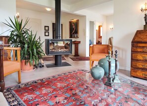 A living room with a fireplace, a large rug, and a wooden cabinet. - Homerez - House in Reignier-Esery (Reignier-Esery)
