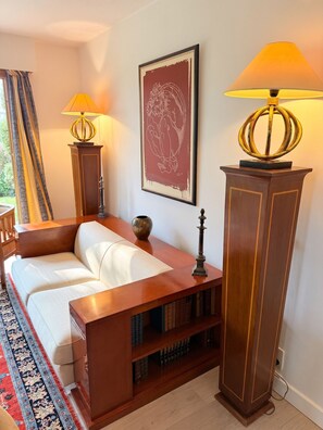 A room with a sofa, a bookshelf, two lamps, a framed artwork, and a patterned rug. - Homerez - House in Reignier-Esery (Reignier-Esery)