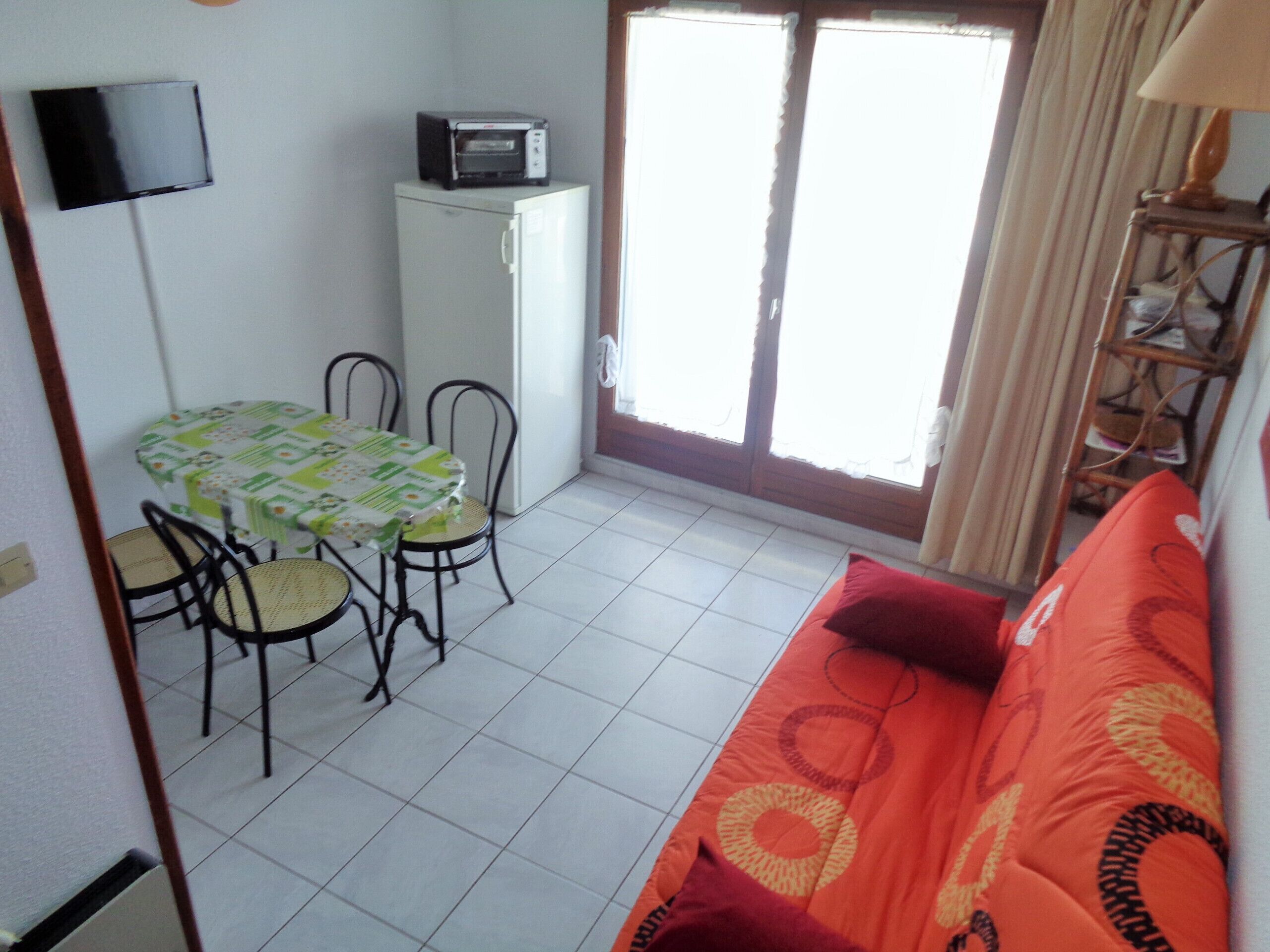 A compact living space with a dining area, a kitchenette, and a sofa.