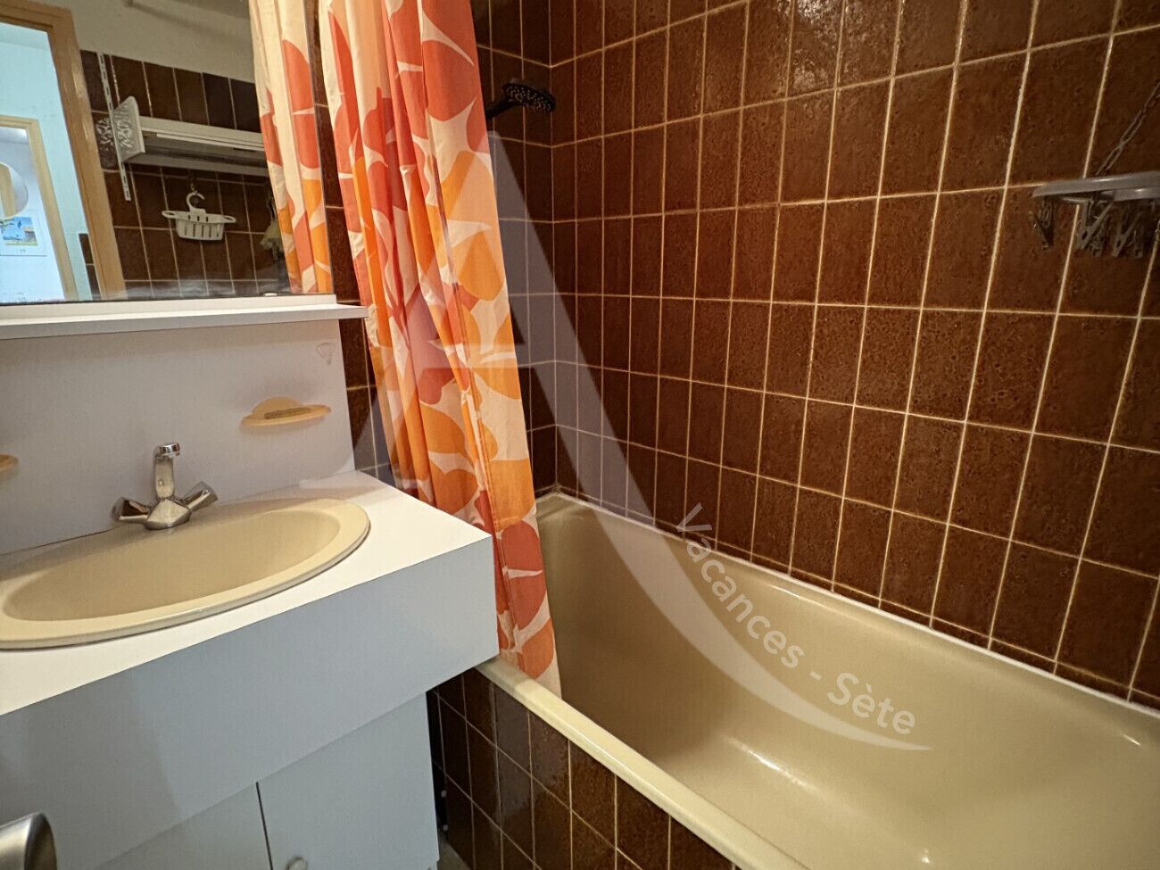 A bathroom with a sink, mirror, and bathtub.