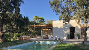 Un área de piscina con sillas de descanso y una zona de estar cubierta.