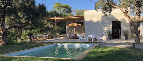 A pool area with lounge chairs and a covered seating area.