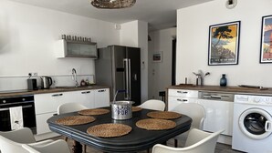Una cocina moderna con una isla central, muebles blancos y lavavajillas integrado.