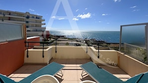 A balcony with two lounge chairs, a view of the sea, and a building in the background. - 2 CHAMBRES, LARGE TERRASSE, 1ERE LIGNE MER (Sète)