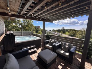 A wooden deck with a hot tub, outdoor seating, and a view of a parking lot and trees. - 1 Brighton modern in downtown's historic district (Charlottetown)