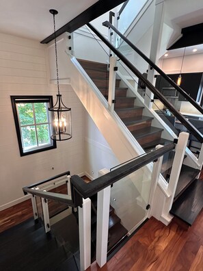 A modern staircase with glass railings and a wooden finish, leading to an upper level. - 1 Brighton modern in downtown's historic district (Charlottetown)