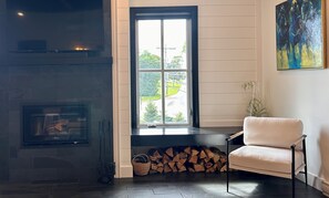 A room with a fireplace, a window with a view, a chair, and a painting on the wall. - 1 Brighton modern in downtown's historic district (Charlottetown)
