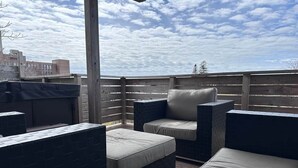 Une terrasse extérieure avec une clôture en bois, un barbecue et des coins salon agrémentés de coussins.
