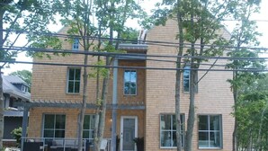 Une maison à deux étages avec un porche couvert, de grandes fenêtres et une porte d’entrée.