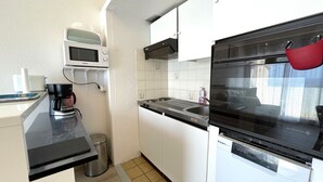 A compact kitchen with a microwave, coffee maker, sink, and oven. - T3 Apartment in Banyuls-sur-Mer, terrace and private parking (Banyuls-sur-Mer)