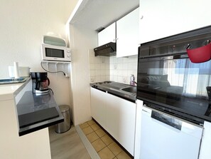 Uma cozinha compacta com micro-ondas, cafeteira, pia e forno.