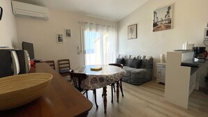 A dining area with a table and chairs, a sofa, a kitchen area with a coffee maker, and a window with curtains. - T3 Apartment in Banyuls-sur-Mer, terrace and private parking (Banyuls-sur-Mer)