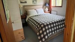 Une chambre à coucher avec un lit, une table de chevet, une lampe et une fenêtre avec des rideaux.