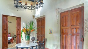 A room with a tiled floor, a chandelier, wooden doors, and a table with chairs. - Casa Sur, Hacienda Living in Merida Centro (Mérida)