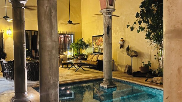 A pool area with columns, a seating area, and a potted plant. - Casa Sur, Hacienda Living in Merida Centro (Mérida)