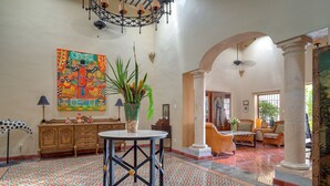 A spacious lobby with a patterned floor, a central round table, and a large colorful painting on the wall. - Casa Sur, Hacienda Living in Merida Centro (Mérida)