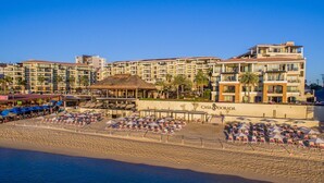 A beachfront hotel with multiple balconies, a pool area, and beachside seating.