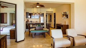 A modern hotel room with a dining area, kitchenette, and a ceiling fan.