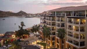 A multi-story hotel with balconies overlooking a beach and the sea.