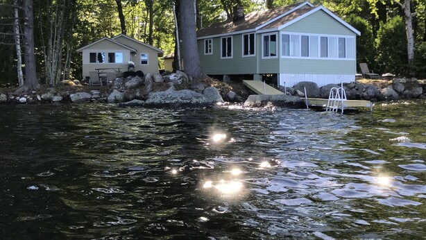 A lakeside cabin with a dock and a small boat. - TWO Waterfront Camps on Sebago Lake (Standish)