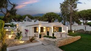 A modern villa with a patio, outdoor seating, and a stone retaining wall. - Vila Balaia - Luxury Boutique Villas (Albufeira)