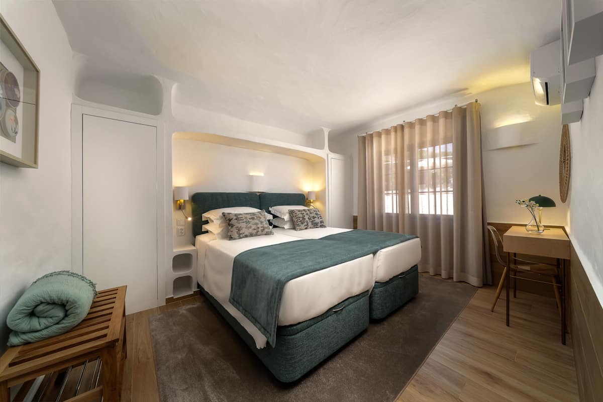 A modern hotel room with a large bed, a desk, and a chair.