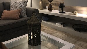 A modern living room with a sofa, decorative items, a TV, and a wooden accent wall. - Vila Balaia - Luxury Boutique Villas (Albufeira)