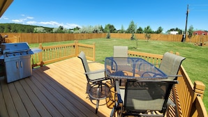 Une terrasse avec un barbecue, des chaises et une table.