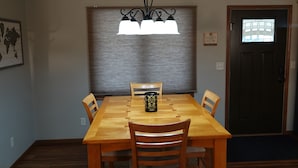 Un coin repas avec une table et des chaises en bois, une décoration murale, une carte du monde et une porte avec une fenêtre.
