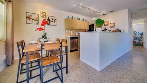 Une cuisine moderne dotée d’un îlot central, d’une table à manger avec des chaises et d’œuvres d’art accrochées aux murs.