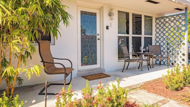 Une maison moderne dotée d’un patio couvert, d’un coin repas avec une table et des chaises, et d’une grande plante en bambou.