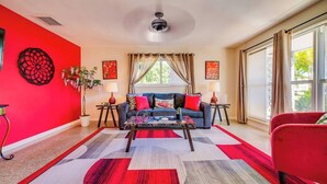 Un salon avec un mur d’accent rouge, un canapé bleu, une table basse et un fauteuil rouge.